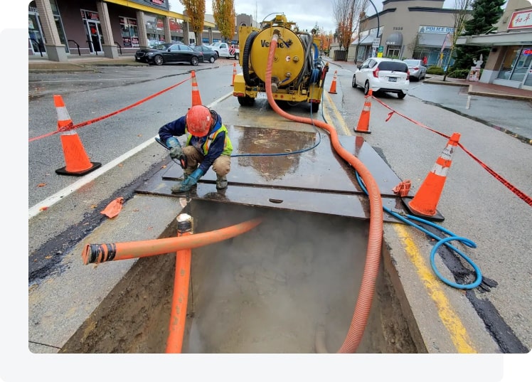 Septic service crew working at an open tank access point beside the truck during a residential visit.